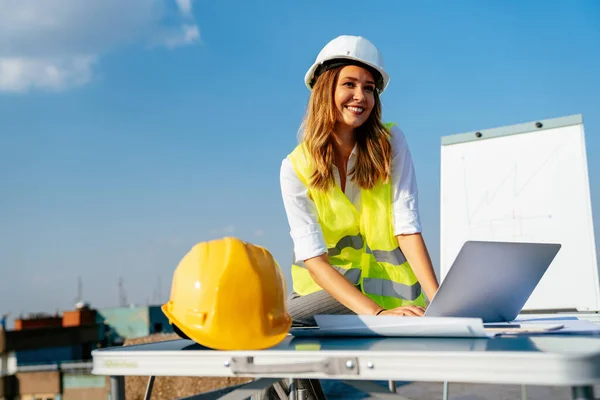 Young successful woman construction specialist architect reviewing blueprints at construction site