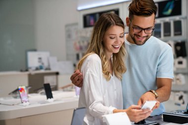 Teknoloji alışverişi dijital cihaz konsepti. Mobil dükkanından yeni bir akıllı telefon alan mutlu gençler.