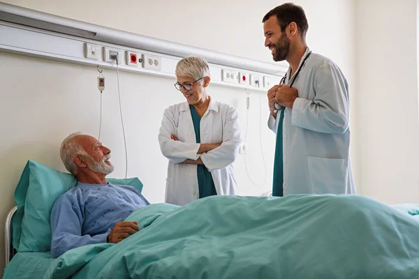 Doctors Consulting Senior Man Patient Hospital Bed Talking Happy Diagnose — Fotografia de Stock