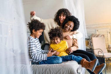 Mutlu çok ırklı aile evde birlikte vakit geçiriyor. Eşcinsel çift çocukları mutluluk kavramını sever