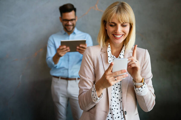Beautiful successful young businesswoman checking emails on the phone in modern office