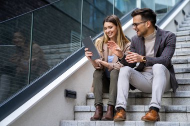 Genç başarılı iş adamlarının portresi, şehir arka planında birlikte çalışıyorlar, konuşuyorlar..