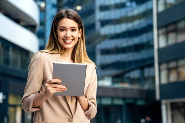 近代的なビジネスビルの前でデジタルタブレットを使用して成功した若いビジネス女性の肖像画 — ストック写真