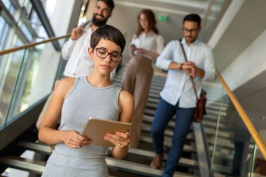 Modern ofisteki iş arkadaşları birlikte çalışıp tablet kullanıyorlar.