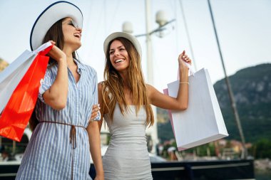 Alışveriş poşetleriyle sokakta yürüyen moda kadınları. Tüketim, satış, alım, alışveriş, yaşam tarzı konsepti.