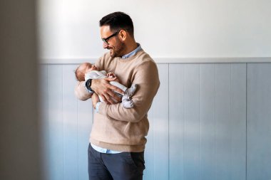 Yeni doğmuş bebeğini kucağında tutan genç babanın yakın plan portresi. Babalık yuvası, yalnız babalar günü konsepti ile birlikte yaşam tarzını sever.