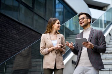 Başarılı iş arkadaşları dijital cihazlar üzerinde birlikte çalışıyorlar. İş adamları şehir konsepti üzerinde çalışıyor