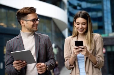 Başarılı iş arkadaşları dijital cihazlar üzerinde birlikte çalışıyorlar. İş adamları şehir konsepti üzerinde çalışıyor