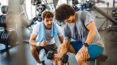Fitness, sport, exercising and diet concept. Happy fit man exercising together with his personal trainer, friend in gym. clipart