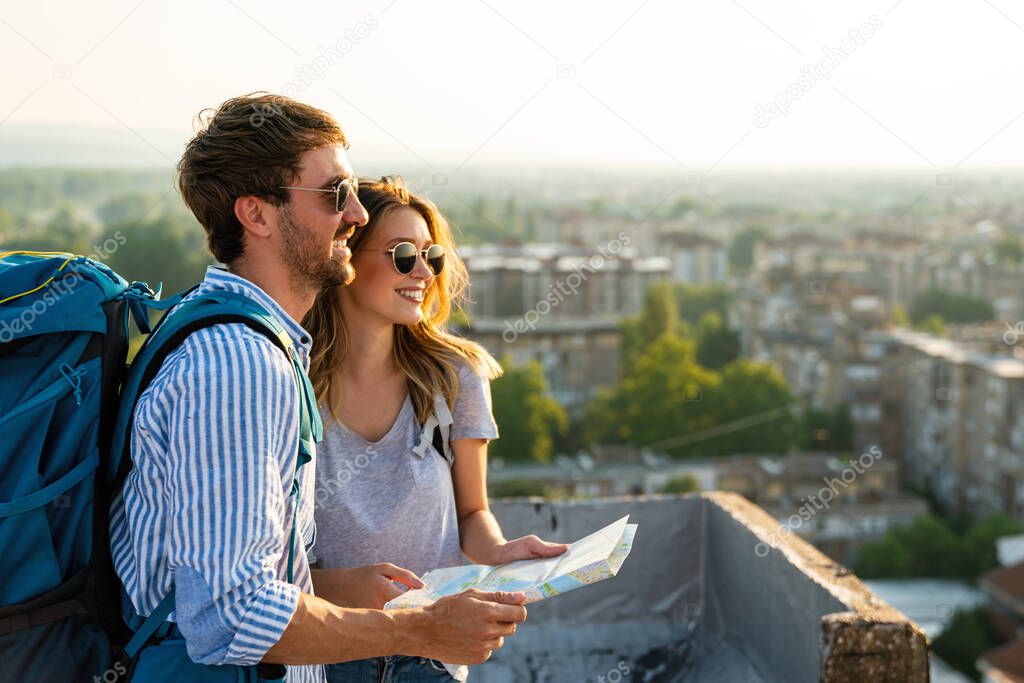 Happy smiling couple on vacation sightseeing city with map. People travel fun love concept.