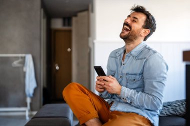 Akıllı telefon konuşmaları sırasında gülen mutlu beyaz adam. Cep telefonu aygıtıyla iletişim kurmak, uygulama kullanan bir adam.
