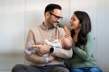 Genç ebeveynlerin ve yeni doğmuş bebeklerin portresi. Baba ve anne yeni doğmuş güzel bir çocuğu öpüp kucaklıyor. Aşk, mutlu babalık ve annelik kavramı..