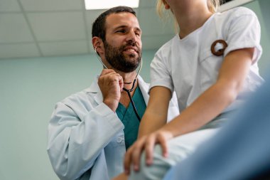 Doktor, muayene odasında steteskopla genç bir kıza check-up yapıyor. Sağlık sektörü çocuk konsepti