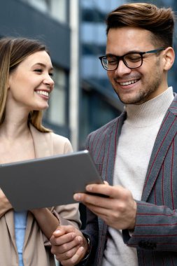 Başarılı iş arkadaşları dijital cihazlar üzerinde birlikte çalışıyorlar. İş adamları şehir konsepti üzerinde çalışıyor