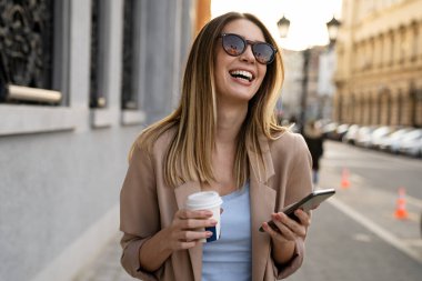 Mutlu iş kadını portresi. Elinde kahve ve dijital tabletle işe gidiyor..