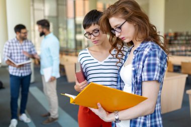Bir üniversite kütüphanesinde birlikte çalışan mutlu bir öğrenci grubu. Eğitim insanları takım çalışması kavramı.