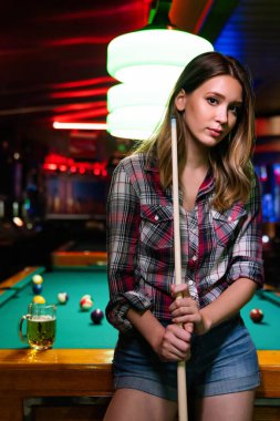 Young beautiful girl is playing billiards. Pleasant pastime, rest, fun entertainment concept