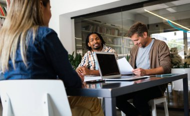Gülümseyen çeşitli meslektaşlar toplantı odasında toplanmış mali istatistikleri tartışıyorlar. Mutlu çok ırklı iş arkadaşları ofis toplantılarında işbirliği yaparken eğleniyorlar. Takım çalışması konsepti.