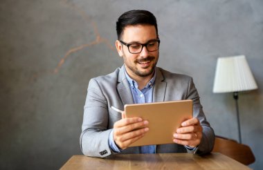 Mutlu halefin portresi genç iş adamı, lider, yönetici dijital tablet kullanarak çalışıyor. İş teknolojisi kavramı.