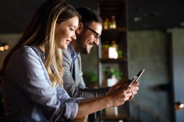 Şirket ofisinde haftalık programı analiz ederken cep telefonu kullanan mutlu bir iş kadını.