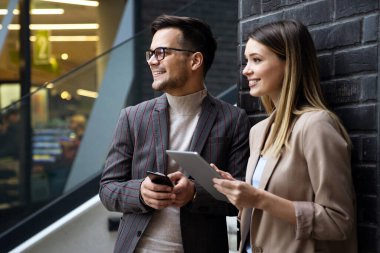 Başarılı iş arkadaşları dijital cihazlar üzerinde birlikte çalışıyorlar. İş adamları şehir konsepti üzerinde çalışıyor