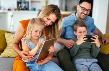 Mutlu genç aile evde eğleniyor. Çocuklu aileler tablet kullanıyor. İnsanlar mutluluk kavramını sever.