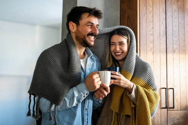 快乐的年轻夫妇 热饮依偎在温暖的毛毯下在家里 人的幸福概念 — 图库照片