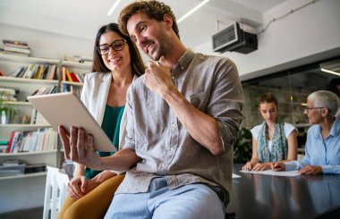 Gülümseyen çeşitli meslektaşlar toplantı odasında toplanmış mali istatistikleri tartışıyorlar. Mutlu çok ırklı iş arkadaşları ofis toplantılarında işbirliği yaparken eğleniyorlar. Takım çalışması konsepti.