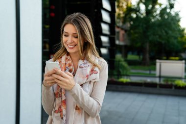 Cep telefonu tutan mutlu bir kadın, cep telefonunda mesajlaşma ve sosyal ağda sohbet ediyor. İnsan teknolojisi kavramı.