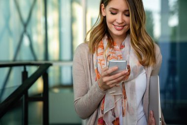 Güzel genç bir iş, dışarıda cep telefonu kullanan öğrenci bir kadın. İnsanlar iletişim teknolojisi kavramı.