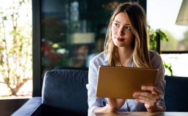 Güzel başarı genç bayan dijital tablet kullanarak çalışıyor. İş, serbest meslek, sosyal medya kavramı.