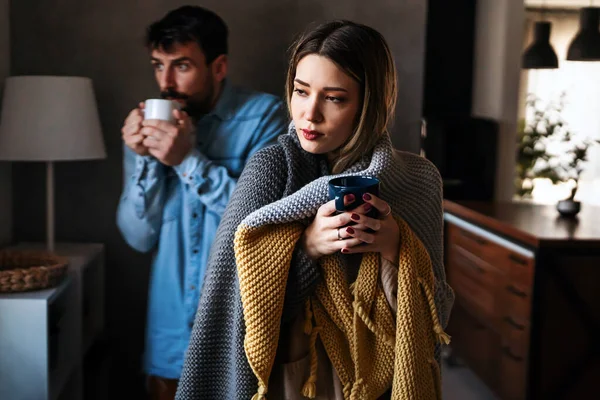 不满意的年轻夫妇在中央取暖 喝热茶等方面都有问题 身患感冒或流感的男女病人裹在毛毯里 — 图库照片