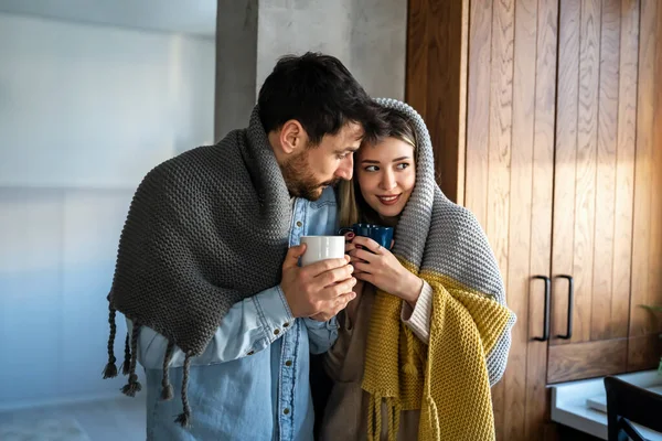 快乐的年轻夫妇 热饮依偎在温暖的毛毯下在家里 周末人们放松爱情的概念 — 图库照片