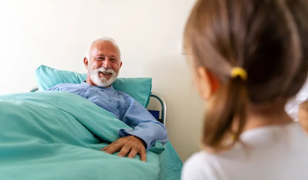 Happy recovering grandfather is visited by his grandchildren in the hospital. Healthcare, family, support concept