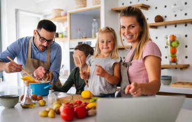 Genç ve mutlu bir aile mutfakta birlikte sağlıklı yemekler hazırlıyor. İnsanlar mutluluk aşçılık konsepti