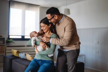 Barışçıl, genç, evli bir çift aile olmanın keyfini çıkarıyor, ebeveynler kucağında yeni doğmuş bir bebek, birbirlerine yakın duruyorlar. Ebeveynlik, doğum, ilişki kavramı