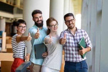 Kütüphanede kitaplarla çalışan mutlu genç üniversite öğrencileri. Üniversitede bir grup çok ırklı insan