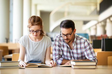 Eğitim kampüsü arkadaşlığı ve insanların konsepti. Bir grup mutlu öğrenci kütüphanede birlikte okuyorlar..