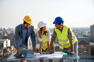 İş, inşaat, takım çalışması ve insan konsepti. İnşaat alanının planlarını taşıyan bir grup mühendis ve mimar.