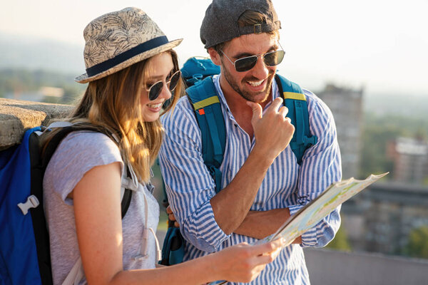 Happy smiling couple on vacation sightseeing city with map. People travel fun love concept.
