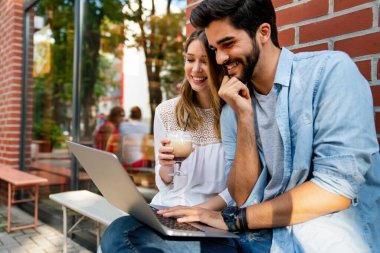 Bilgisayarda ve dijital cihazlarda çalışan mutlu genç çift. İş, eğitim insanları kavramı.