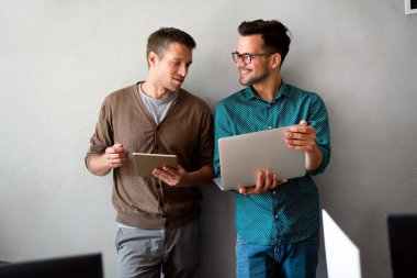 Yönetim kurulunda dikilirken dijital tablet kullanan iki genç iş adamı. İki iş arkadaşı toplantı sırasında tartışıyorlar. Çeşitli iş adamları takım olarak çalışıyor..