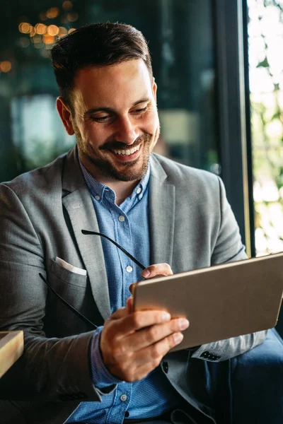 Gülümseyen başarılı iş adamı, resmi iş süitinde dijital tablet üzerinde çalışan girişimci
