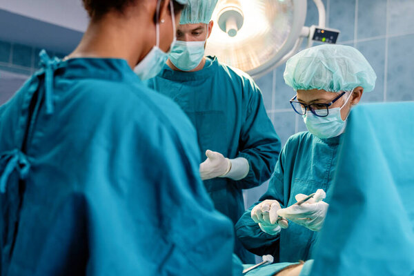 Portrait of successful team of surgeon standing in operating room, ready to work on a patient