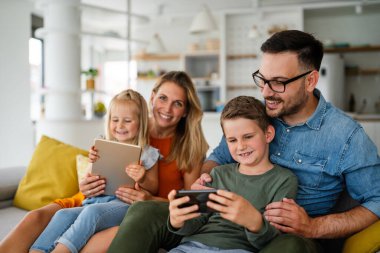 Dijital cihaz teknolojisi aile çevrimiçi eğitim kavramı. Evde dijital cihazları olan mutlu genç bir aile..