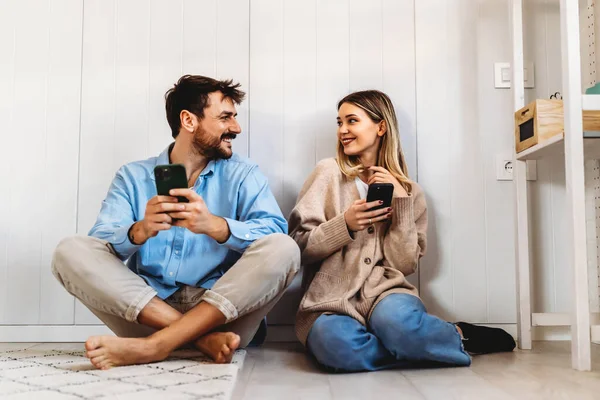 看着智能手机 笑着拥抱的年轻夫妇 多种族夫妇在智能手机上共享社交媒体 — 图库照片