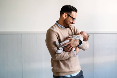 Yeni doğmuş bebeğini kucaklayan ve öpen bir babanın portresi. Erkek ebeveyn çocuğunu tutuyor. Otantik yaşam tarzı dokunaklı bir an. Bekar baba aile hayatı konsepti.