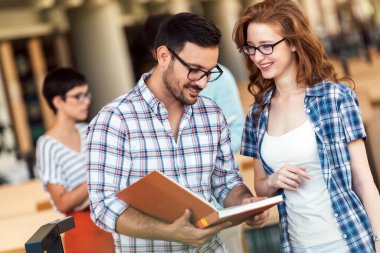 Bir üniversite kütüphanesinde birlikte çalışan mutlu bir öğrenci grubu. Eğitim insanları takım çalışması kavramı.