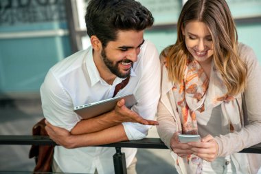 Mutlu genç iş adamları dışarıda dijital cihazlar kullanarak sohbet ediyorlar. İnsanlar teknoloji iş kavramı.