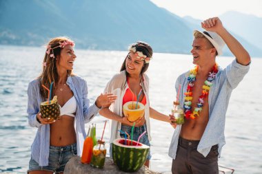 Bir grup mutlu arkadaş plaj partisinde tropikal kokteyllerle eğleniyor. Seyahat ve yaz tatili konsepti.